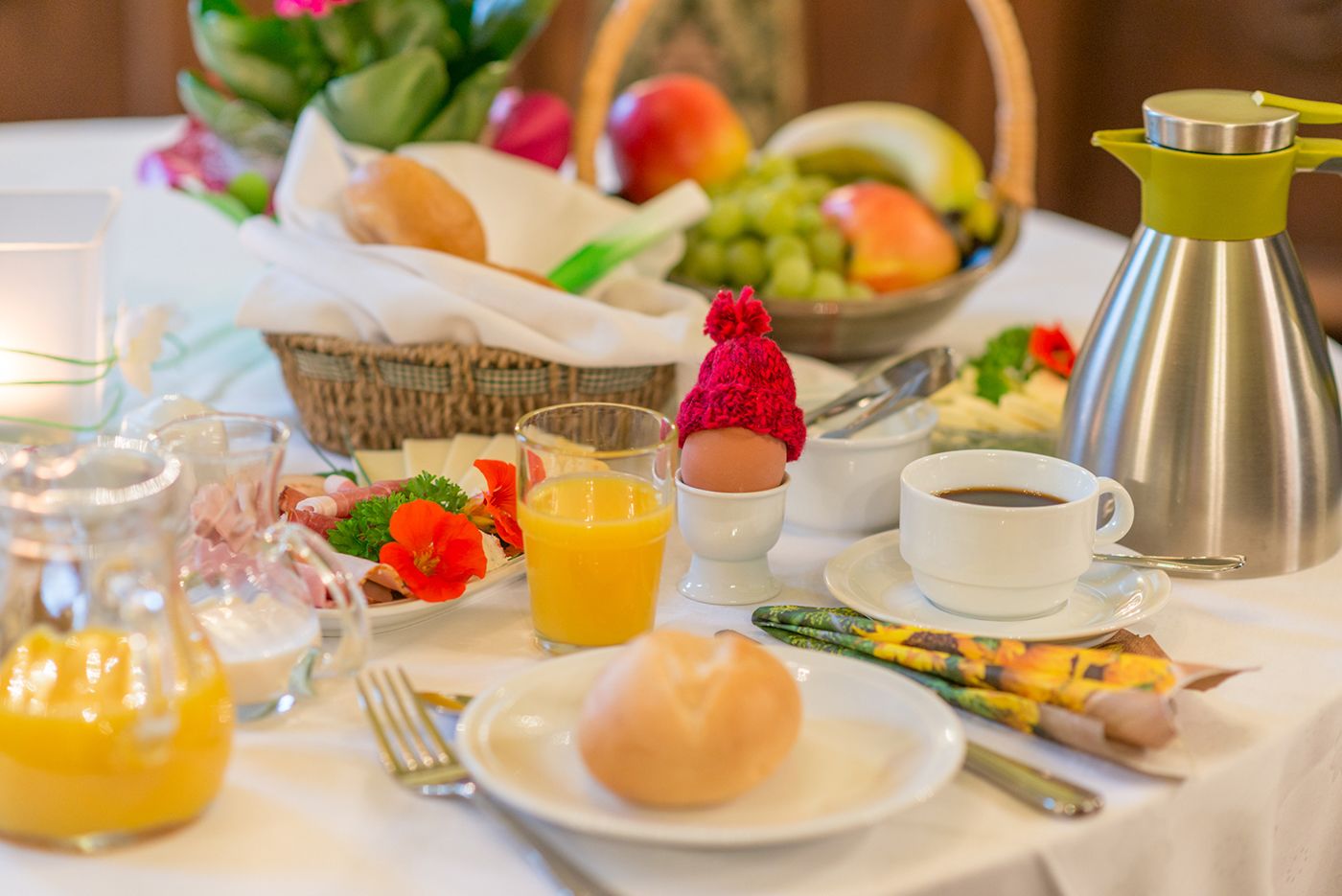 A breakfast setting with a variety of foods, including eggs, fruits, and beverages, arranged on a table.