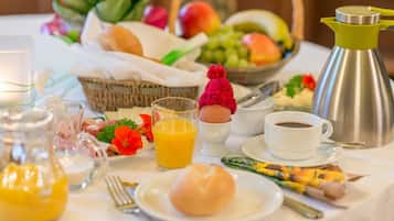 A breakfast setting with a variety of foods, including eggs, fruits, and beverages, arranged on a table.