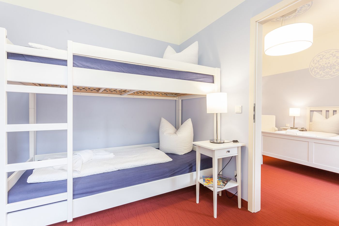 A bunk bed room with a desk and a mirror.