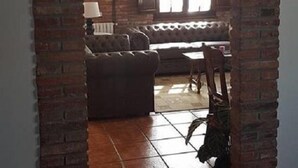 An arched brick doorway leading to a living room with a sofa, a table, and a window. - Posada La Cerrá de San Roque (Santillana del Mar)