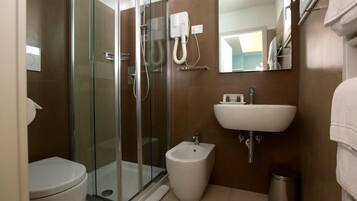 A bathroom with a glass-enclosed shower, a pedestal sink, and a toilet.