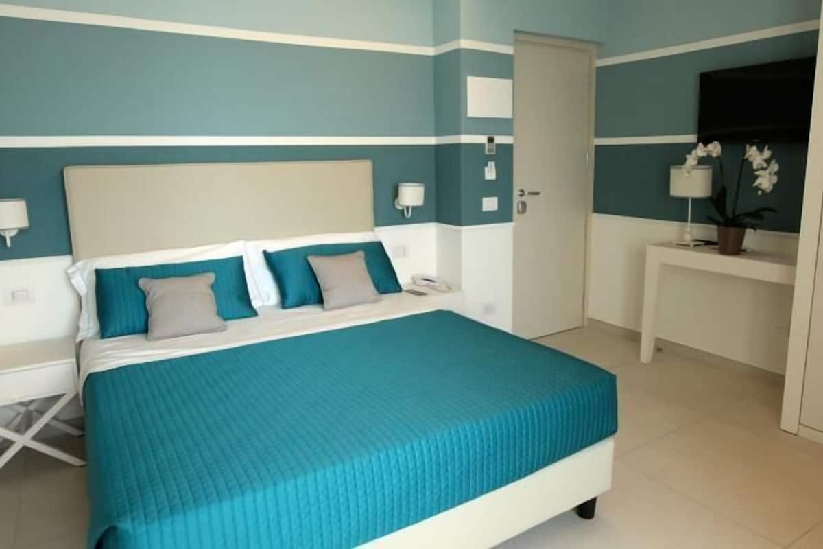 A bedroom with a bed, bedside tables, a desk, and a wardrobe.
