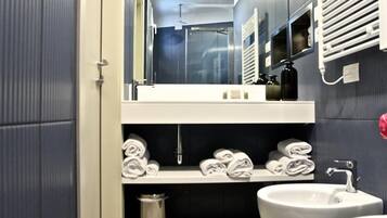 Un bagno moderno con lavandino bianco, specchio e spazio per gli asciugamani.