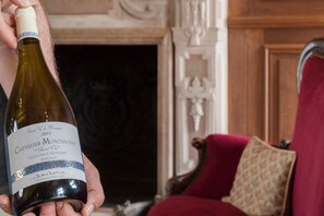A person holding a bottle of wine with a label that reads "Chevalier-Montrachet Grand Cru CLOS DES CHEVALIERS Monopole." - Château Saint-Michel, The Originals Relais (Relais du Silence) (Rully)
