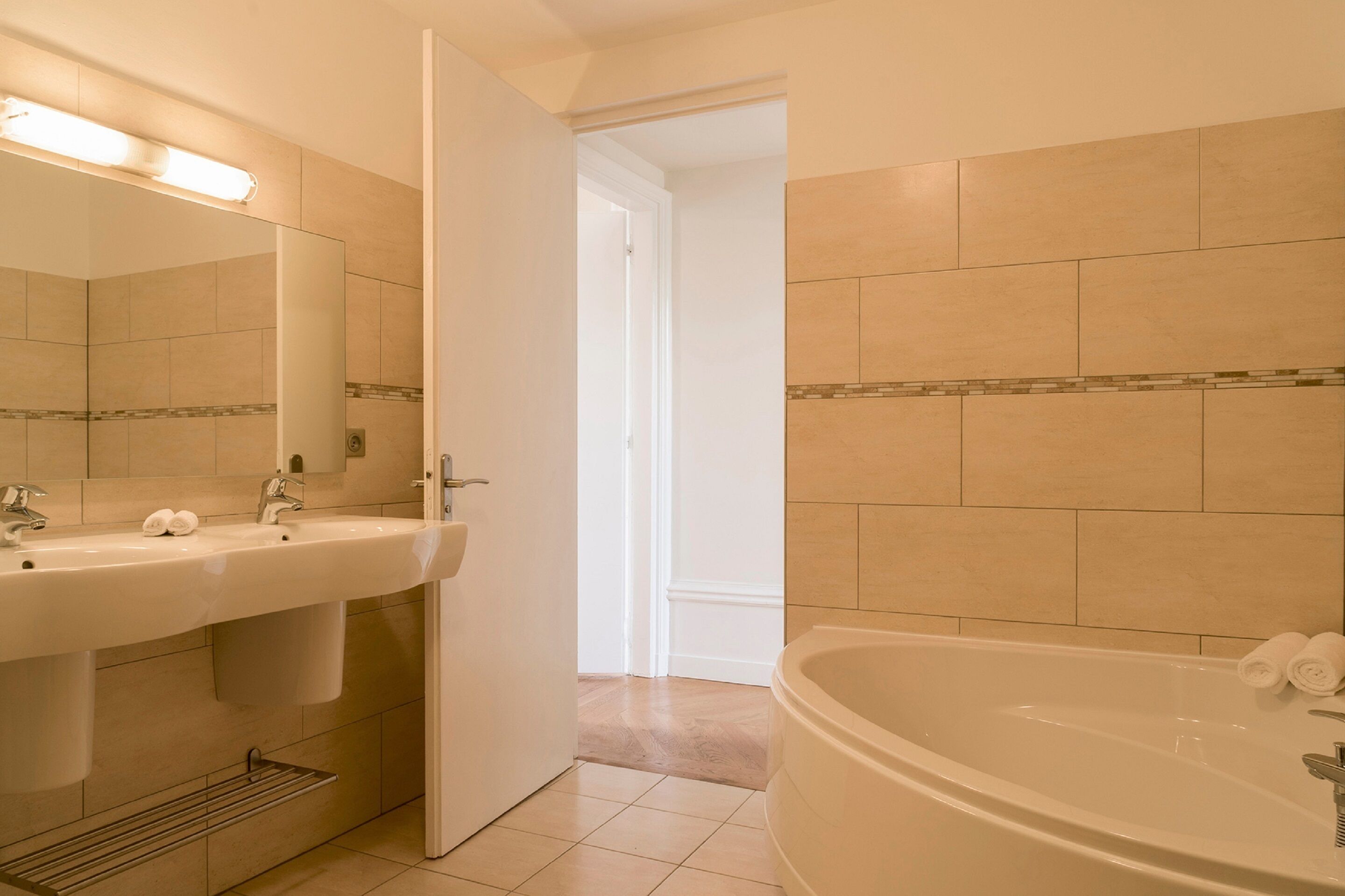 Un baño con lavamanos, espejo y bañera.
