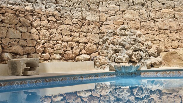 A stone wall with a pool area. - Palazzo Violetta (Sliema)