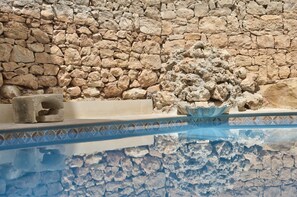 A stone wall with a pool area. - Palazzo Violetta (Sliema)