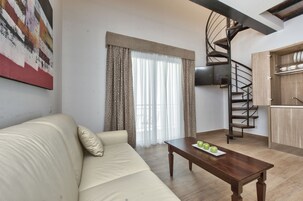 Una sala de estar con sofá, una mesa de centro con manzanas, una escalera en espiral y una zona de cocina.