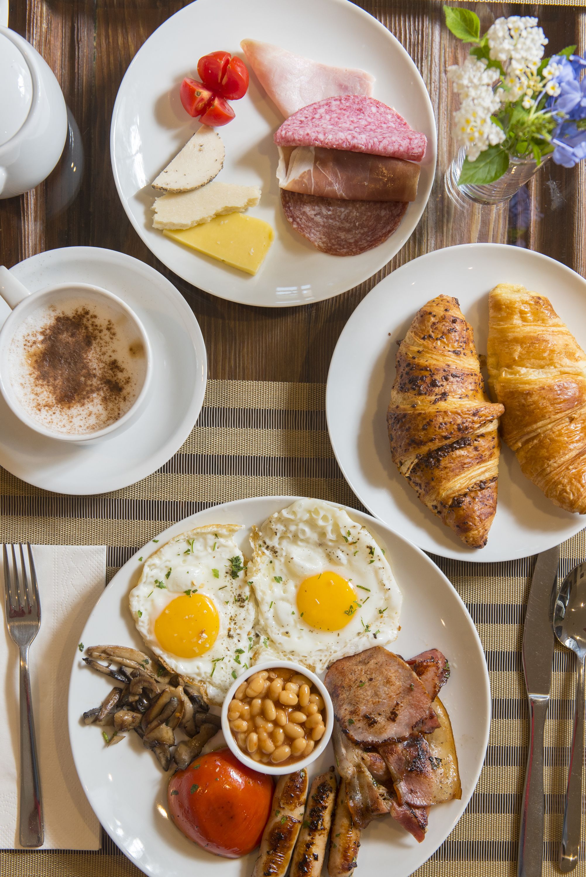 Ein Frühstücksteller mit Eiern, Schinken, Pilzen, Bohnen und Tomaten.