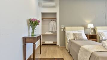 Habitación de hotel con cama, mesitas de noche, escritorio, armario y un florero.