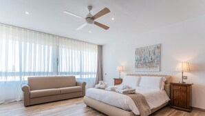A bedroom with a bed, a sofa, a ceiling fan, and a painting on the wall. - Palazzo Violetta (Sliema)
