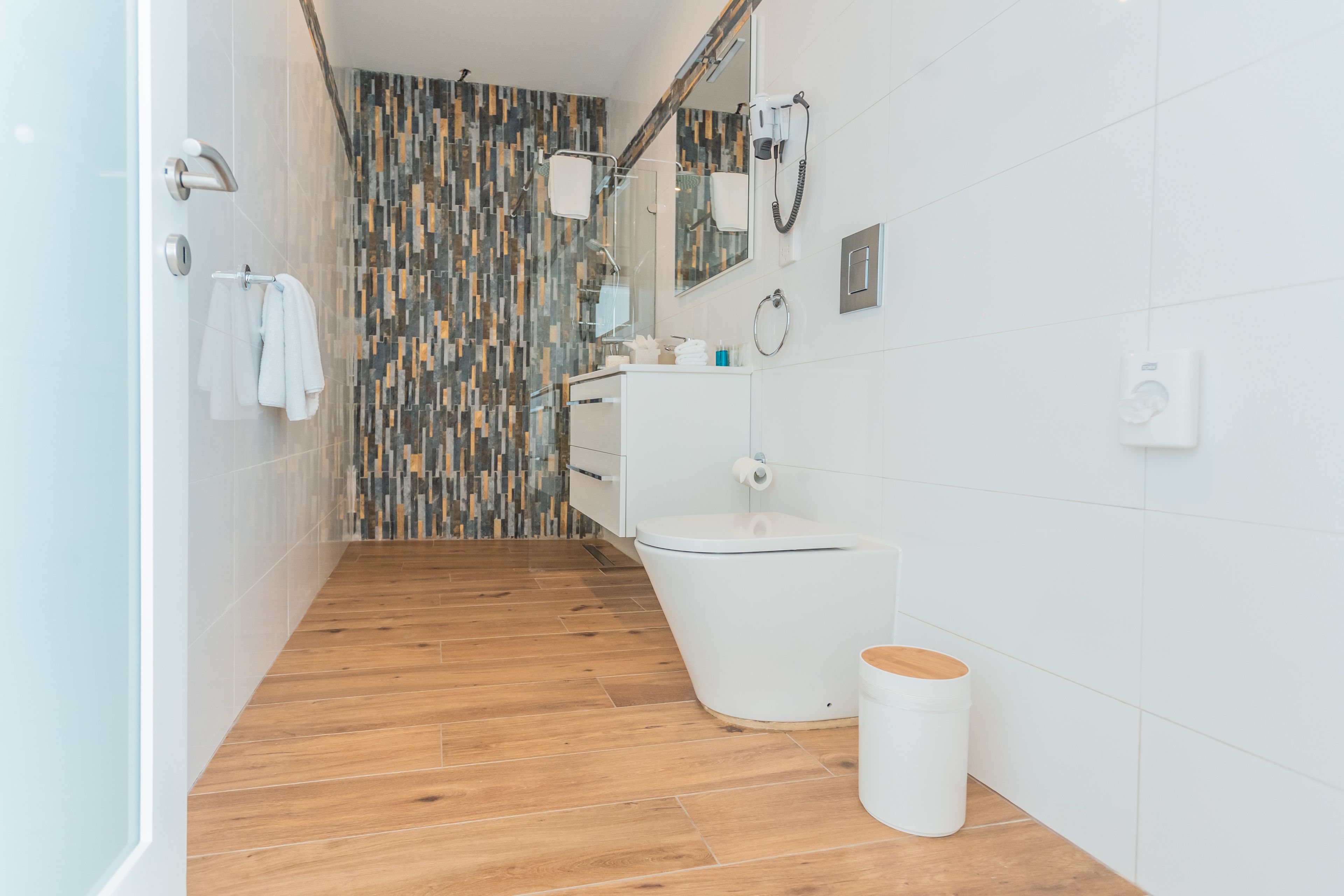A modern bathroom with a shower, toilet, and sink.