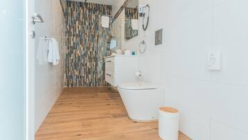 A modern bathroom with a shower, toilet, and sink.