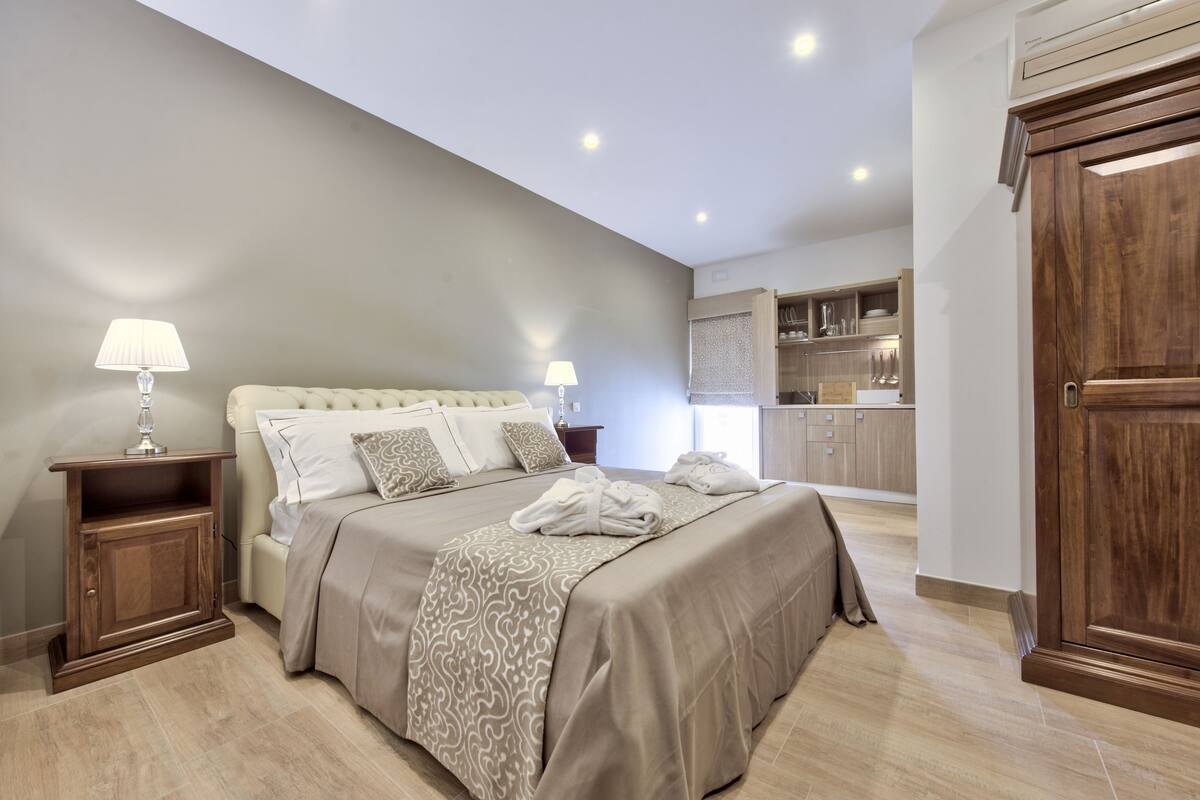 Un dormitorio con una cama grande, mesitas de noche y vistas a la cocina.