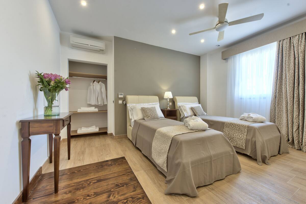 Una habitación de hotel con dos camas, un escritorio, un tocador y una ventana con cortinas.