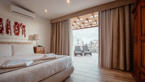 A hotel room with a large bed, a nightstand, a lamp, and a view of the balcony. - Palazzo Violetta (Sliema)