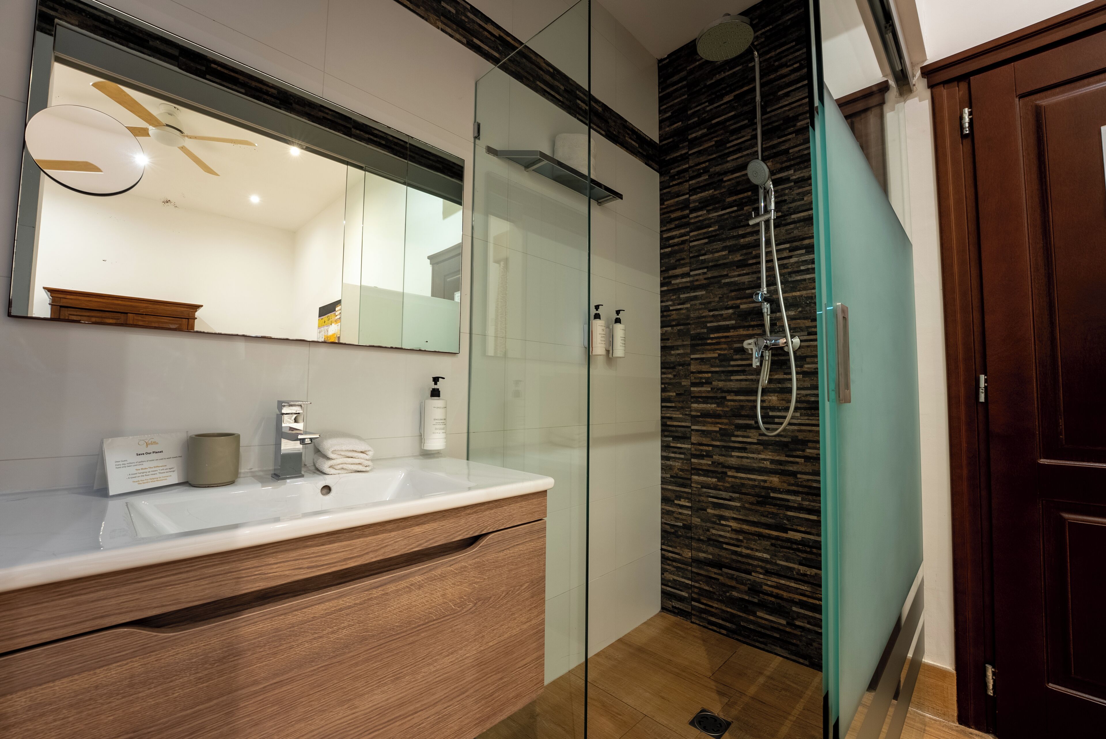 Une salle de bain moderne avec une douche à parois de verre, un meuble-lavabo en bois et un grand miroir.
