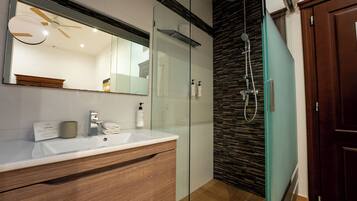 Une salle de bain moderne avec une douche à parois de verre, un meuble-lavabo en bois et un grand miroir.