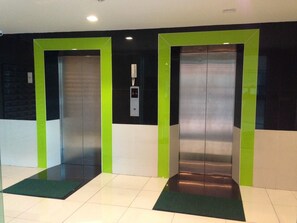 Two elevators with green accents in a modern building. - iPREMIUM Sukhumvit 81 (Bangkok)