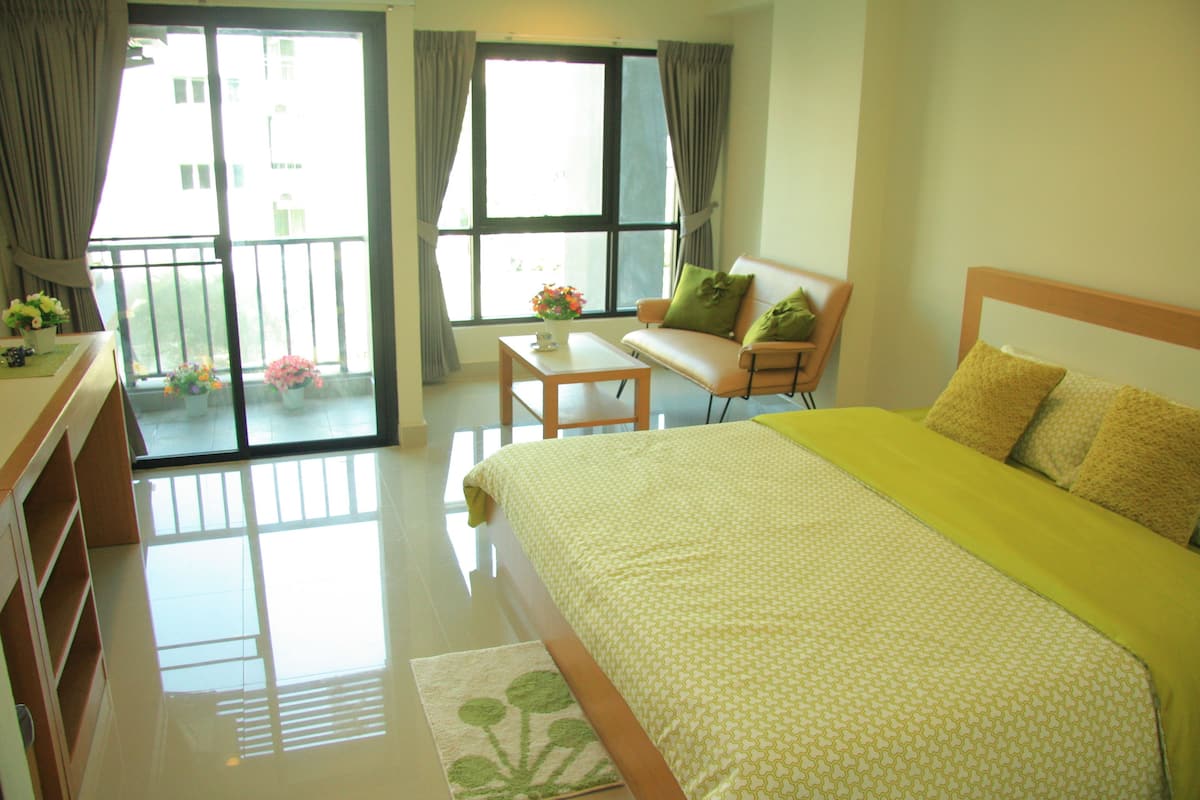A hotel room with a bed, a sofa, a table, and a window with curtains.