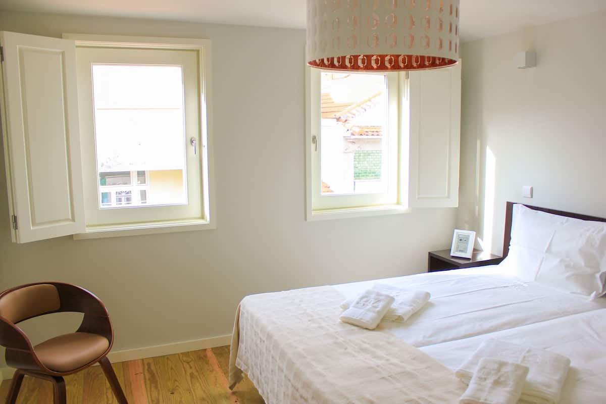 Une chambre d’hôtel avec deux lits, une chaise, une table de chevet et une fenêtre.