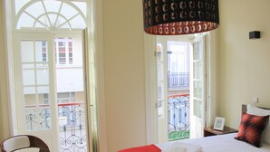 Ein Hotelzimmer mit Bett, Stuhl und einem Balkon mit Geländer.