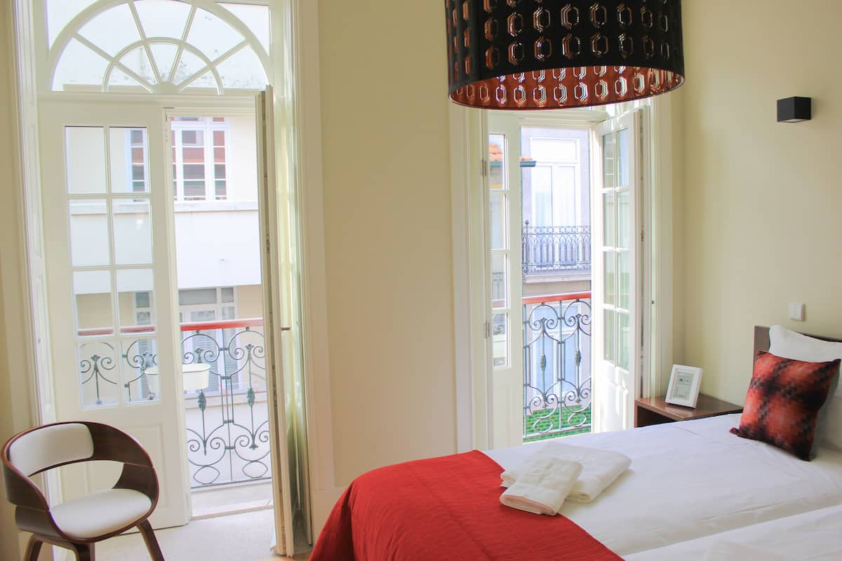 Une chambre d’hôtel avec un lit, une chaise et un balcon doté d’une rambarde.