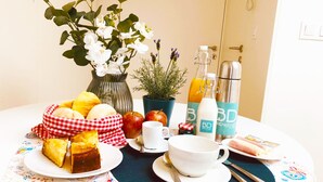 Ein Frühstückstisch mit Brot, Obst und einer Kaffeekanne.