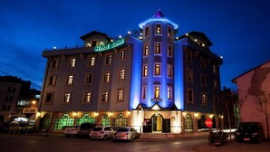 Un hôtel à plusieurs étages, doté d’une tour imposante et d’une enseigne indiquant « Hôtel Rumi ».
