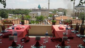 A restaurant with tables set for dining, overlooking a cityscape with historic buildings and a mosque.