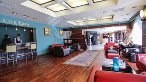 Un hall d’hôtel comprenant un comptoir d’accueil, un espace salon et un escalier menant aux étages supérieurs.