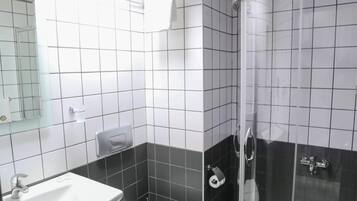 A modern bathroom with a white sink, toilet, and a glass-enclosed shower area.