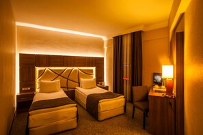 A hotel room with two beds, a desk with a chair, a TV, and a lamp.