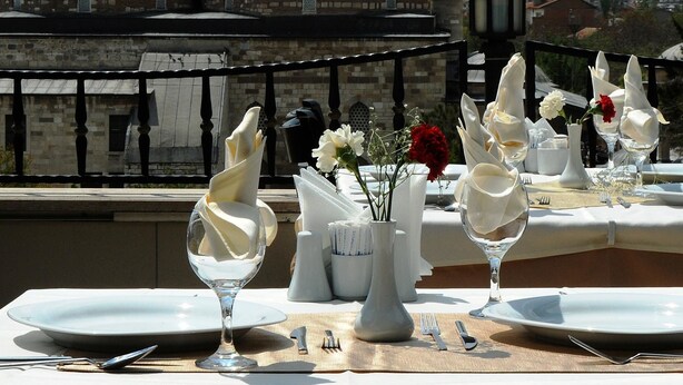 Une table dressée pour un dîner à deux, avec en arrière-plan une vue sur des bâtiments historiques.