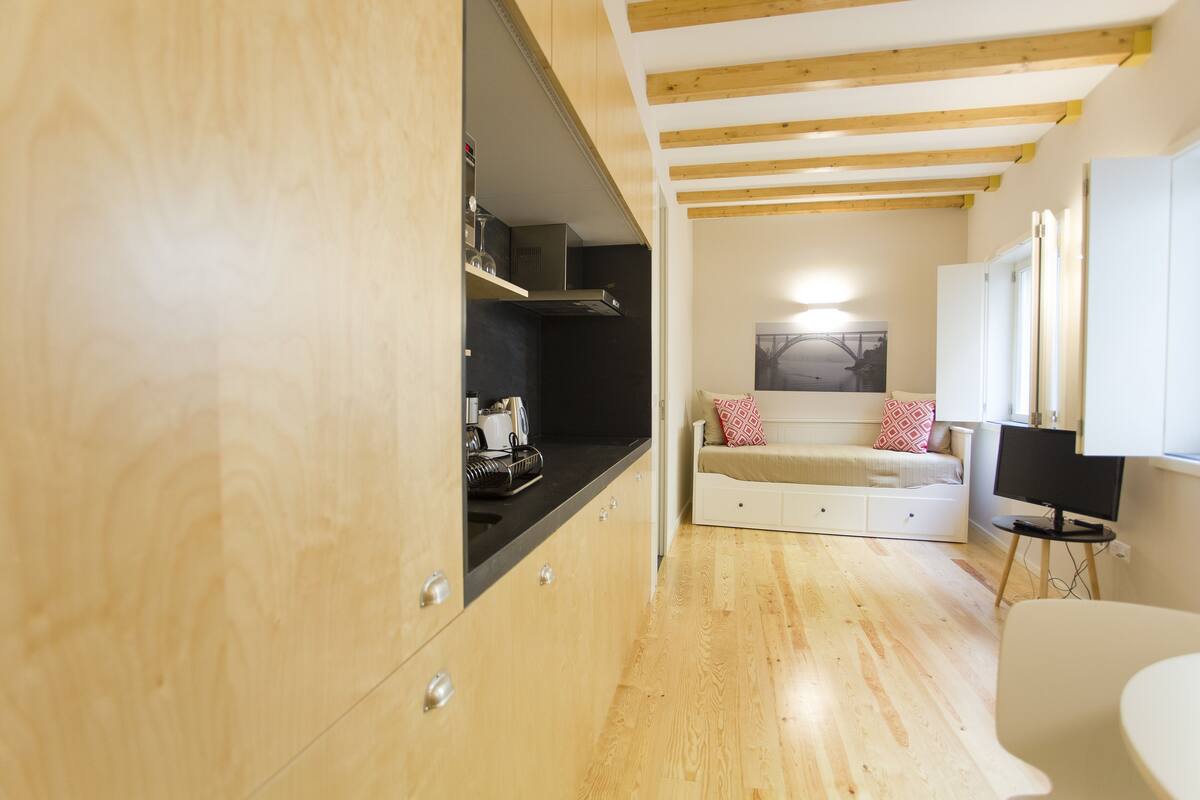 A compact kitchen with wooden cabinets, a black countertop, and a built-in stove.