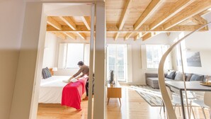 A modern interior with a wooden ceiling, a bed with a red blanket, a sofa, and a dining area. - Oporto Trendy River (Porto)