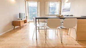 A modern kitchen with a wooden countertop, white chairs, and a dining table. - Oporto Trendy River (Porto)