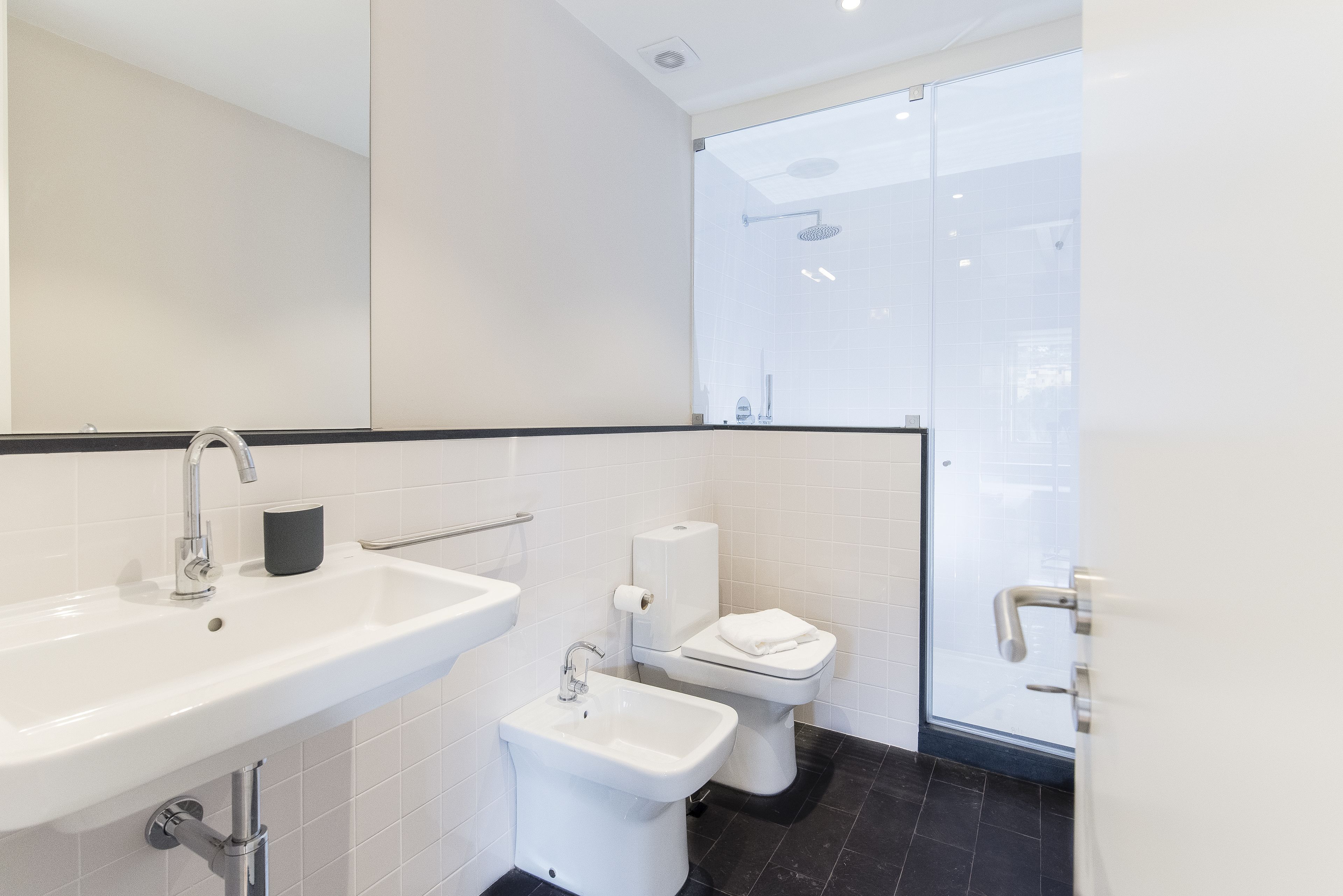 Een moderne badkamer met een witte wastafel, een toiletbrons en een toilet.