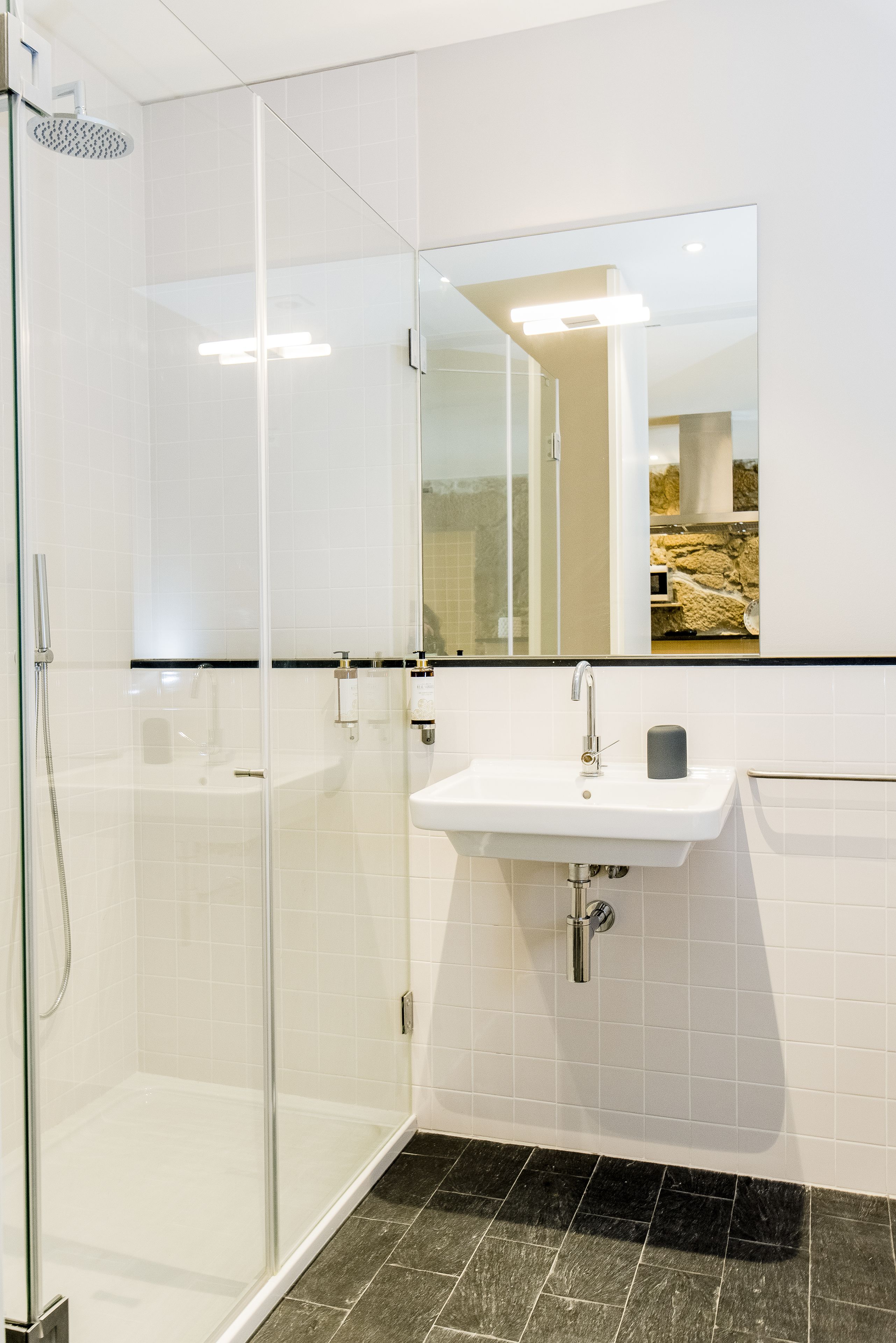 A modern bathroom with a glass-enclosed shower, a white sink, and a mirror above it.