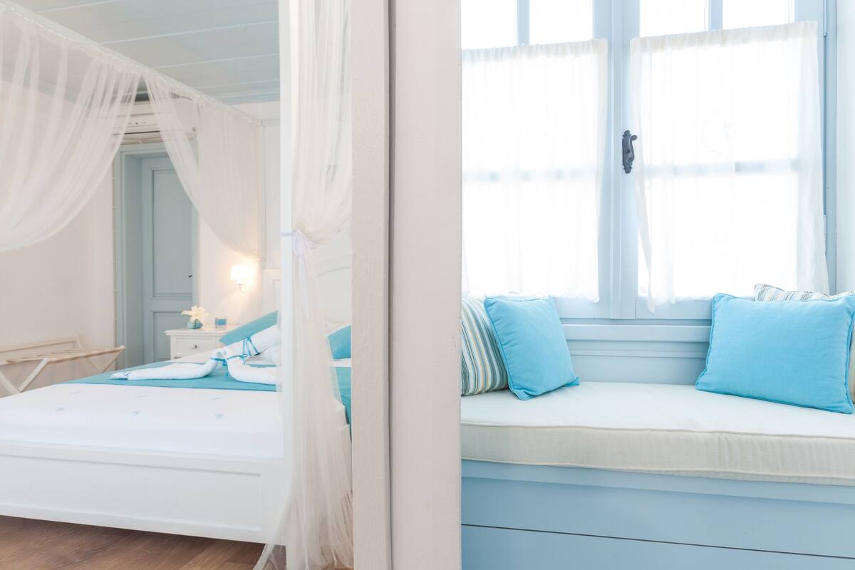 Ein Schlafzimmer mit einem Bett, einer Sitzbank an einem Fenster und einem Himmelbett.