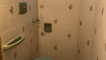 A small bathroom with two toilets, a sink, and a shower.