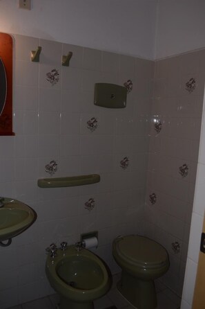 Un baño con bidé, inodoro y lavamanos.