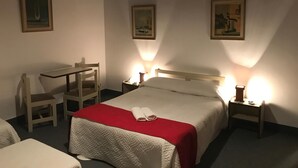 A hotel room with a bed, a desk, two chairs, and two bedside lamps. - Hotel Antares (Montevideo)