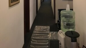 A hotel hallway with framed artwork on the walls, a reception desk, and a water dispenser. - Hotel Antares (Montevideo)