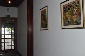 A hallway with a door leading to a room, a framed painting on the wall, and a sign above the door. - Hotel Antares (Montevideo)