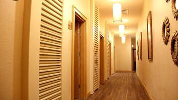 Un pasillo de hotel con pisos de madera, paredes color beige y puertas con listones horizontales.