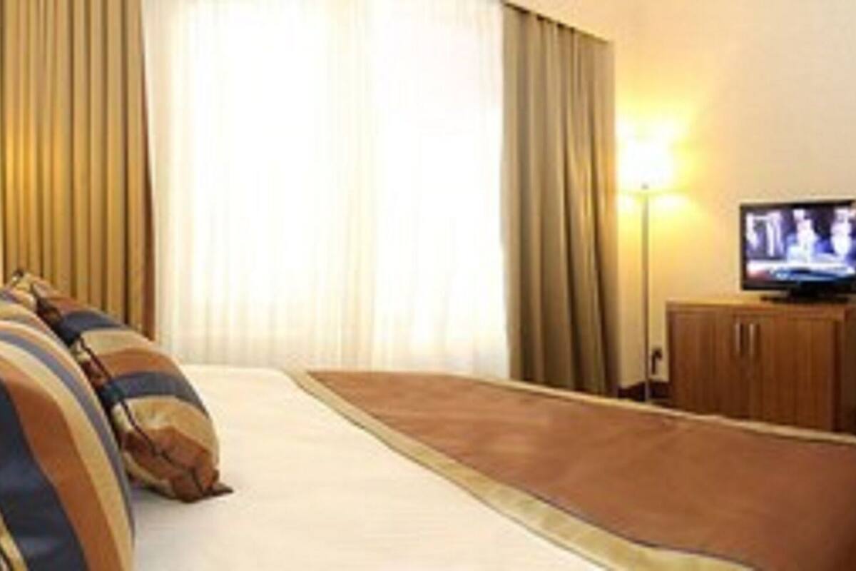 Una habitación de hotel con una cama, almohadas, un televisor y una puerta.