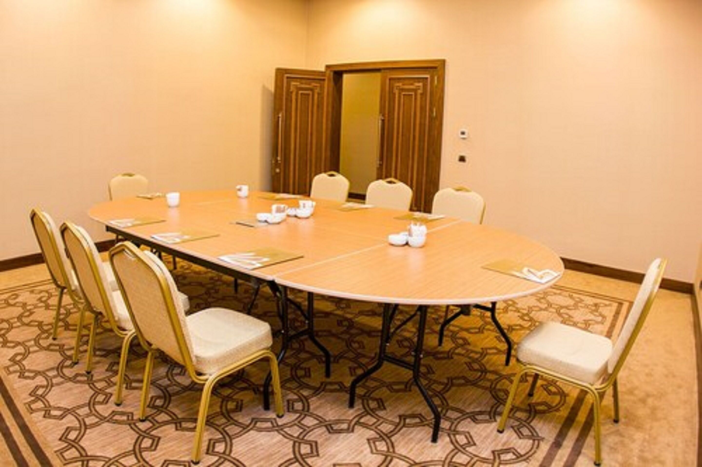 A conference room with a round table, white chairs, and a carpeted floor.