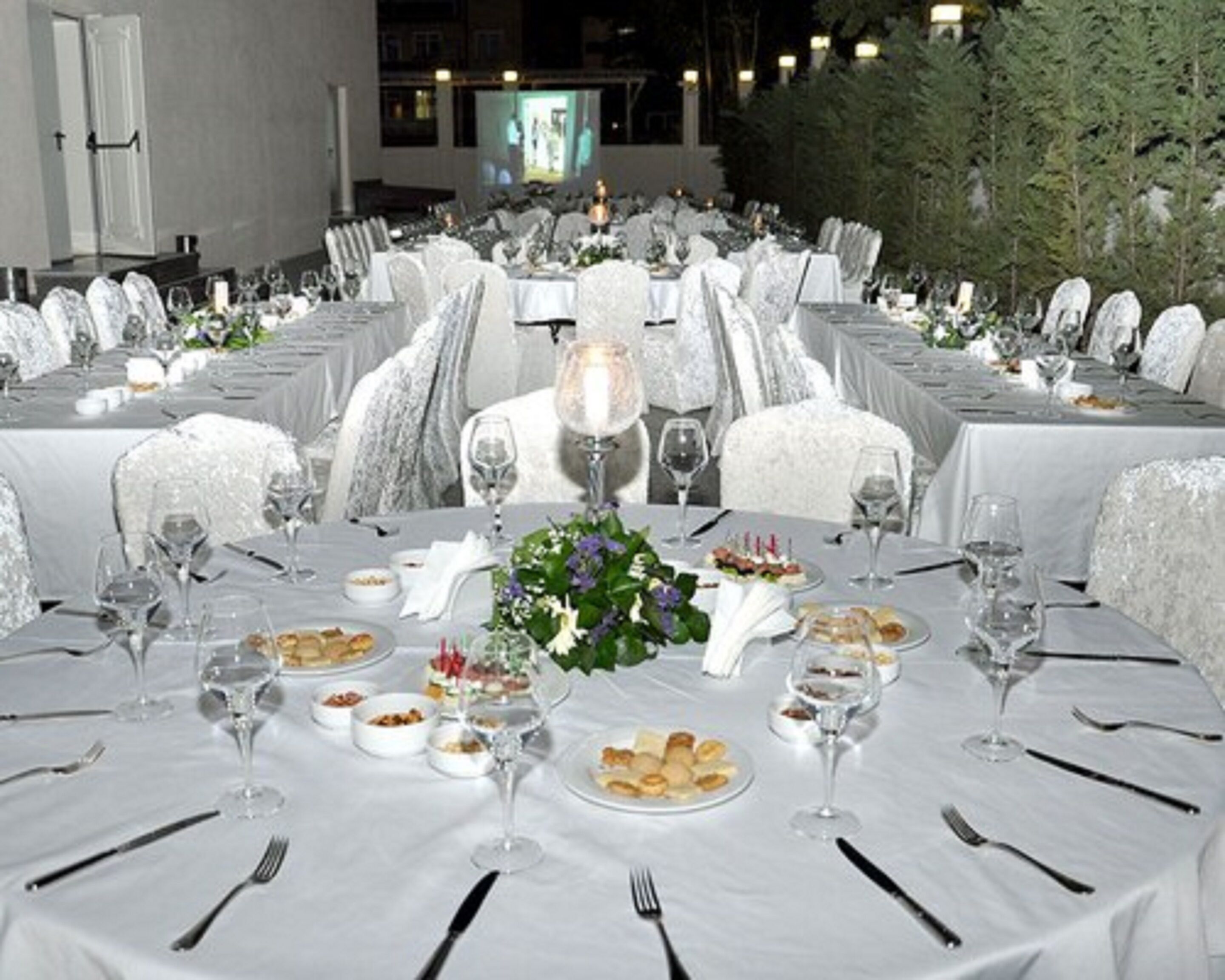 A formal dining area with round tables, white tablecloths, and chairs.