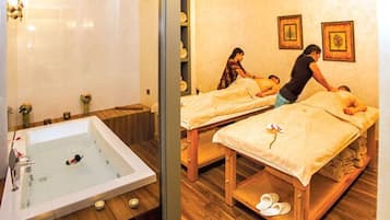 Relax in a serene spa room with a large hot tub and two massage tables.